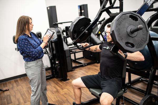A personal trainer working with a client while using StrengthPortal on an iPad